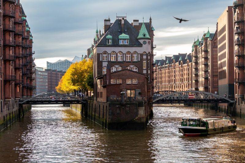 Während der Klassenfahrt nach Hamburg unternimmt die Schulklasse eine spannende Stadtführung durch St. Pauzli, Speichersatdt und Hafen. Auf dem Bild sehen wir die historischen Backsteingebäude der Hamburger Speicherstadt umgeben von Wasser und verbunden durch zwei Brücken.