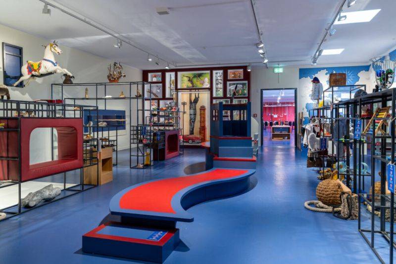 Die Wunderkammer im Altonaer Museum, welche die Schüler während der Klassenfahrt nach hamburg besucehn. Ein Innenraum mit Regalen, zahlreichen Artefakten und einem blauen Fußboden.